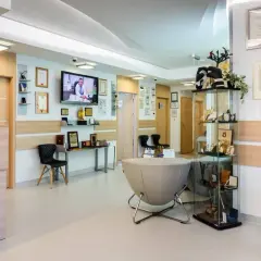 Nowoczesne wnętrze recepcji kliniki medycznej z meblami, dyplomami i telewizorem.