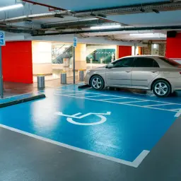 Miejsce parkingowe dla osób z niepełnosprawnościami, symbol wózka inwalidzkiego. Ułatwienia dla niepełnosprawnych przy rejestracji samochodu.