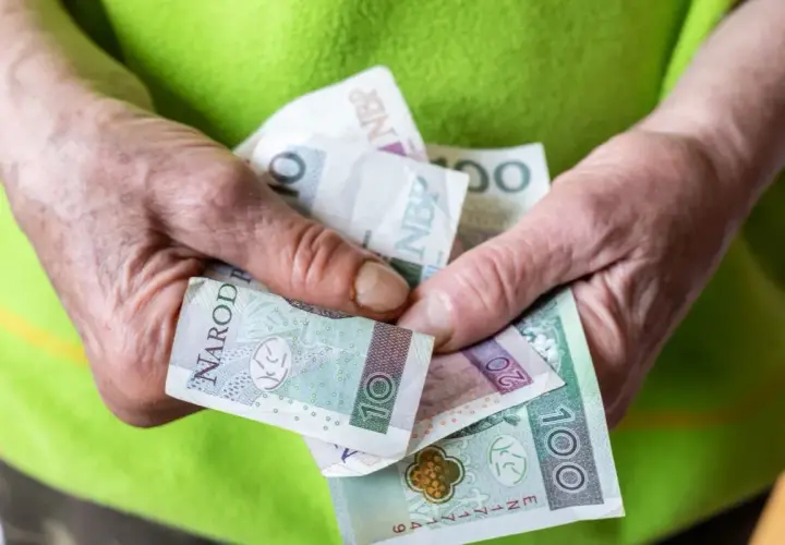 Dłonie trzymają polskie banknoty: 10, 20 i 100 zł. Zastanawiasz się, ile wynosi renta socjalna z MOPS?