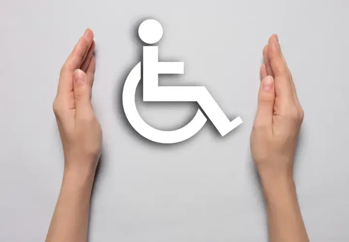 Symbol wózka inwalidzkiego otoczony dłońmi. Symbolizuje wsparcie dla osób z niepełnosprawnością, np. po mastektomii.