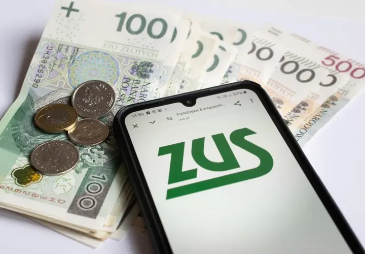 ZUS na ekranie telefonu obok polskich banknotów i monet. Symbolizuje to świadczenia związane z częściową niezdolnością do pracy.