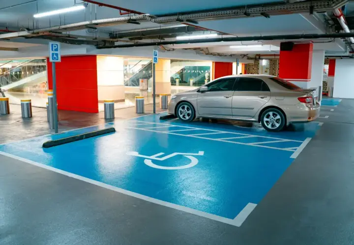 Miejsce parkingowe dla osób z niepełnosprawnościami, symbol wózka inwalidzkiego. Ułatwienia dla niepełnosprawnych przy rejestracji samochodu.