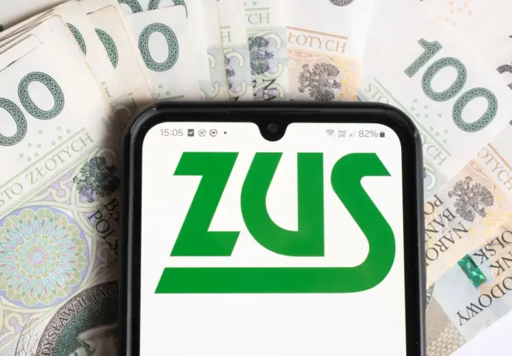 ZUS na ekranie telefonu, otoczony banknotami 100 zł. Symbolizuje to świadczenia, np. dodatek do emerytury dla 1 grupy inwalidzkiej.