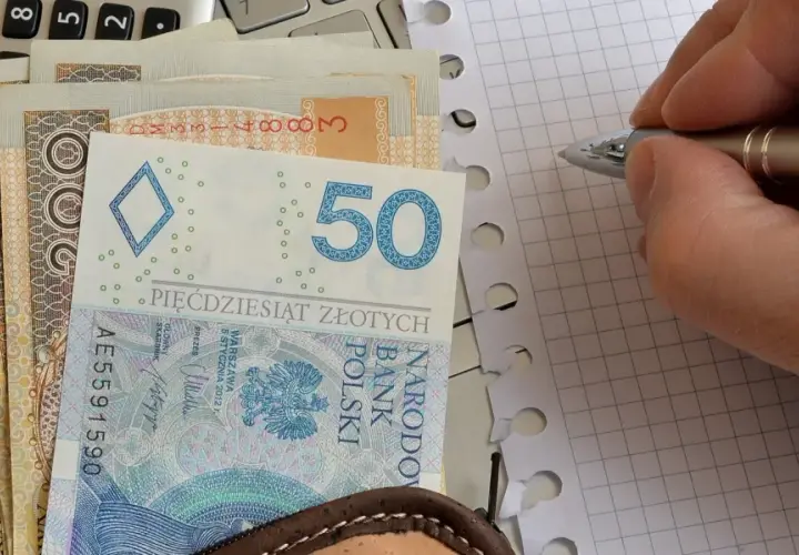 Zasiłek pielęgnacyjny to wsparcie dla osób potrzebujących. Na zdjęciu polskie banknoty, kalkulator i notatnik.