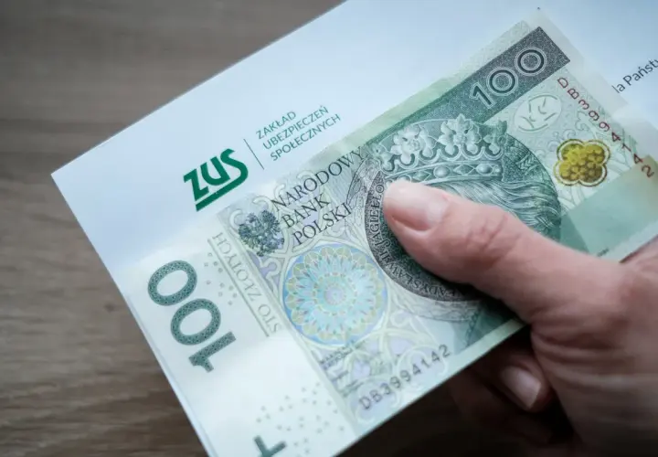 Dłoń trzyma banknot 100 zł i dokument ZUS. Może to symbolizować wsparcie finansowe, np. renta na depresję.